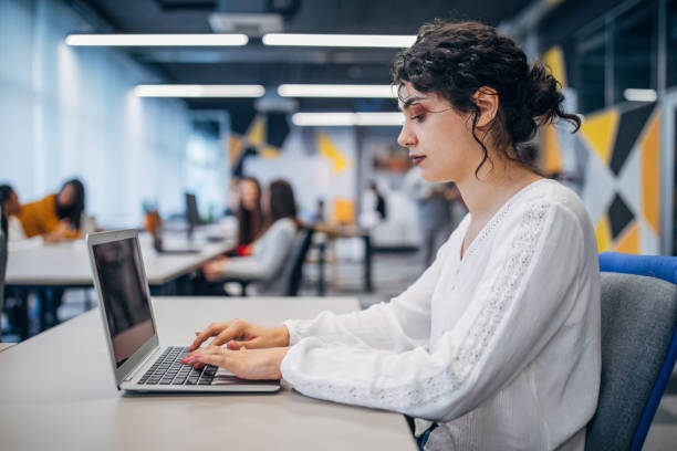 istock Beautiful woman working on laptop in big modern office 1203730149