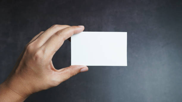 istock Hand holding mockup white business card on black background. 1203730228