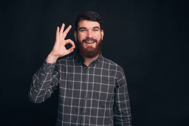istock Bearded man is showing ok or just perfect gesture on dark background. 1203730300