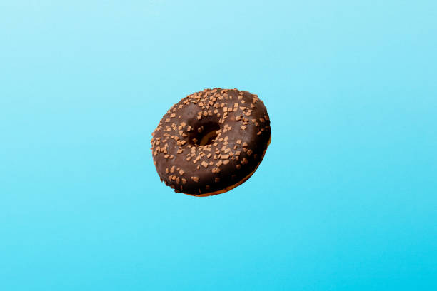 istock Flying in air donut with chocolate icing on a blue background. Bakery, baking concept. Levitation 1203733776