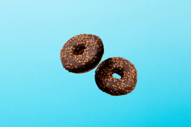istock Flying in the air Donuts with chocolate icing on a blue background. Bakery, baking concept. Levitation 1203734628