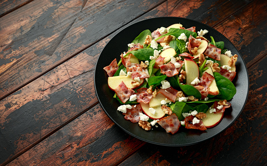 Bacon, Apple Salad with spinach, walnuts and feta cheese. on wooden table. healthy food