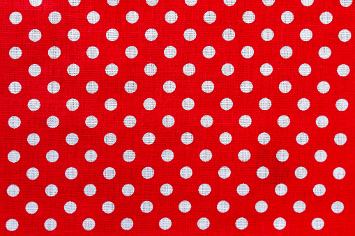 Polka dot on red canvas cotton texture. Red fabric with printed white circles. Bright colored cotton background