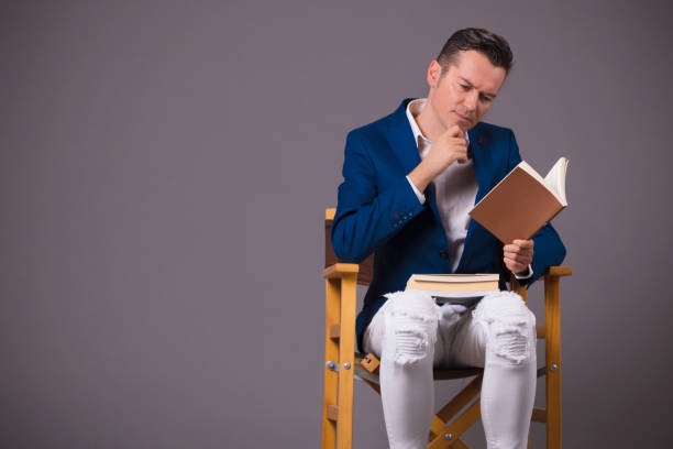 istock Pensive man reading book against gray background. 1203734951