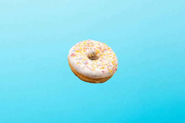 istock Flying in air donut with white icing on a blue background. Bakery, baking concept. Levitation 1203734989