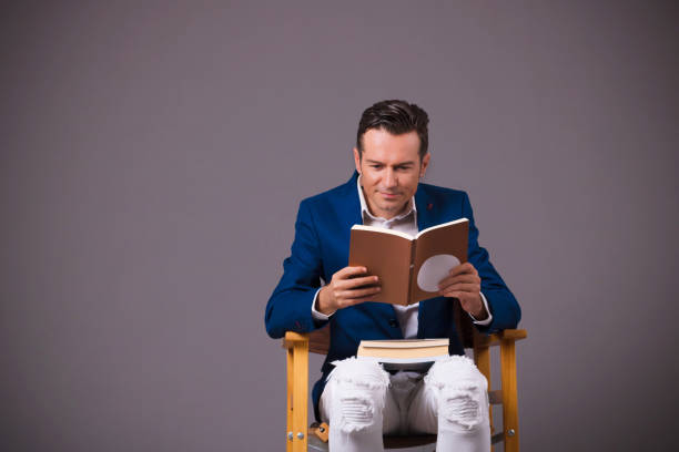 istock Smiling man reading book against gray background. 1203735101