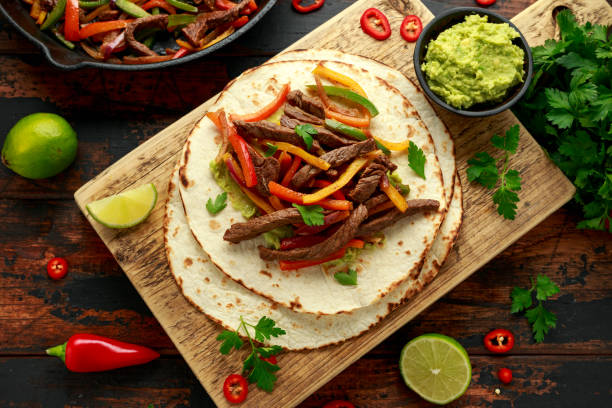 Beef Steak Fajitas with tortilla mix pepper, onion and avocado on wooden board Beef Steak Fajitas with tortilla mix pepper, onion and avocado on wooden board. fajita photos stock pictures, royalty-free photos & images