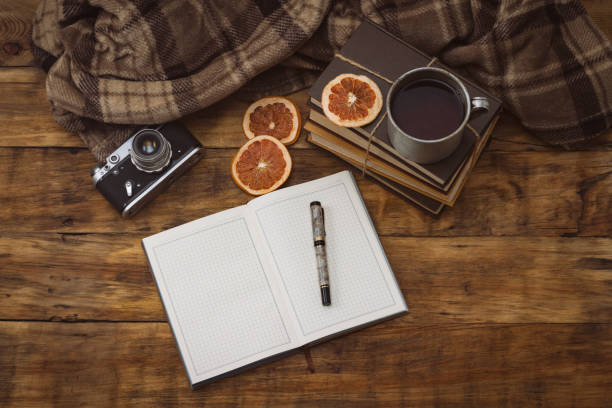 journal avec le stylo, livres, tasse de cru en aluminium avec le thé chaud, appareil photo antique et coins secs de pamplemousse sur un fond en bois - book school desk old photos et images de collection