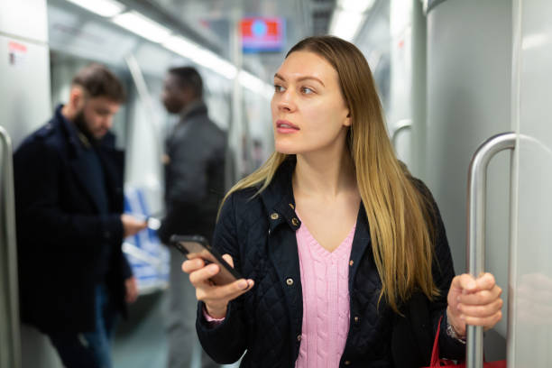 istock Young woman with phone in subway car 1203741126