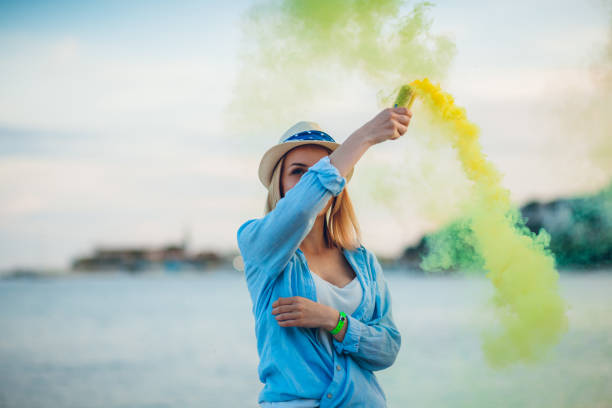 istock Woman having fun with smoke bomb on the beach 1203741921