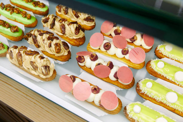 istock Eclair, Cakes with cream, nuts and decorations, stacked in a row on a display case, confectionery 1203742049