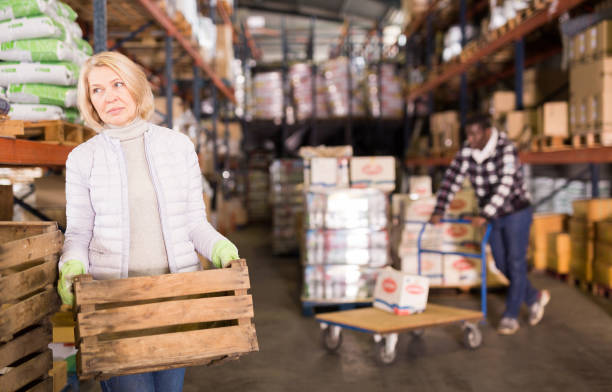 istock Woman warehouse worker carrying wooden boxes 1203742155