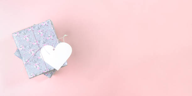 istock Valentine's day mockup banner. Gift boxes wrapped with grey paper with floral pattern and white paper heart  on pink. 1203742879