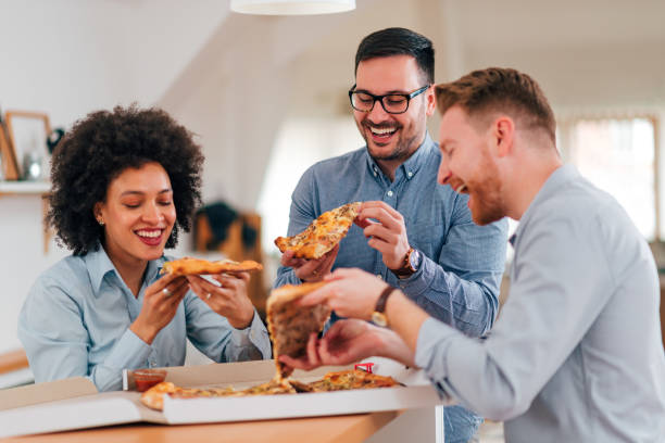 istock Smiling group of people eating pizza on a break. 1203743864