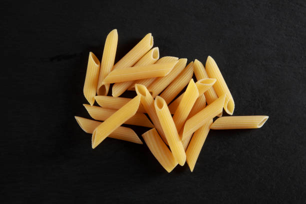 istock Raw Durum Wheat Penne Pasta on black background 1203745864