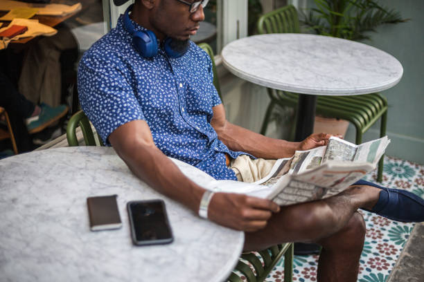 istock Modern young man reading newspaper in the coffee shop while waiting for coffee 1203749936