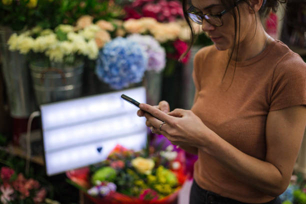 istock Modern female florist looking for online orders on her mobile phone 1203750538
