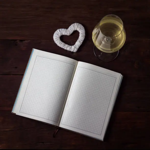 Open Diary, White Heart HyundaiBokal with White Wine on a Wooden Table.