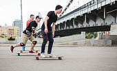 Modern young male skateboarders skating under bridge in Moscow