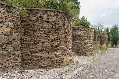 Stone wall. Hand made stone constructions. Columns made of stone and clay, external decoration of the territory.