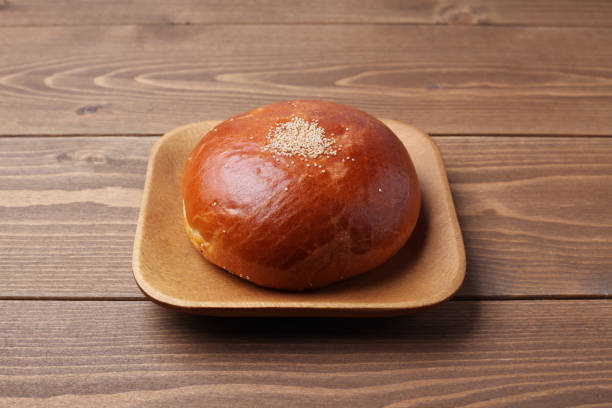 анпан круглый хлеб с azuki красной фасоли пасты изолированы на тарелке на деревянном столе - 2655 стоковые фото и изображения