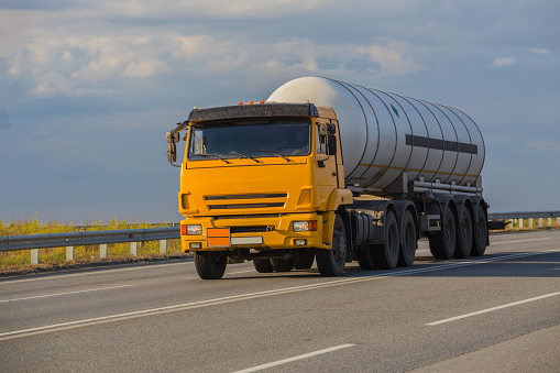 Truck with a liquefied gas tank moves along a suburban highway