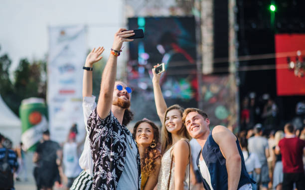 groupe de jeunes amis avec le smartphone au festival d’été, prenant le selfie. - music festival park friendship summer photos et images de collection