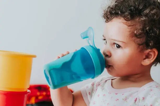 Stock photo of a little girl drinking water from her blue water bottle.