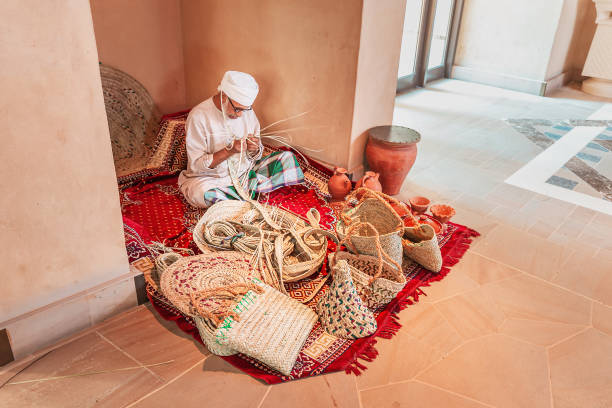 An old artisan weaves baskets for sale in the interior of a shopping Mall 27 November 2019, Dubai, United Arab Emirates: An old artisan weaves baskets for sale in the interior of a shopping Mall bamboo twist stock pictures, royalty-free photos & images