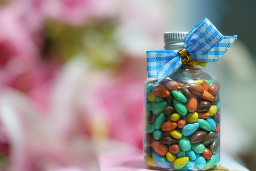 Colorful chocolate-coated sunflower seeds in a glass bottle tied with a blue ribbon