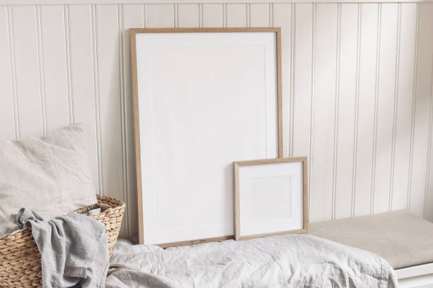 istock Portrait and square empty wooden frame mockups with straw basket and linen cloth. White beadboard wainscot wall paneling background. Scandinavian interior, home design. Art concept. 1203759625