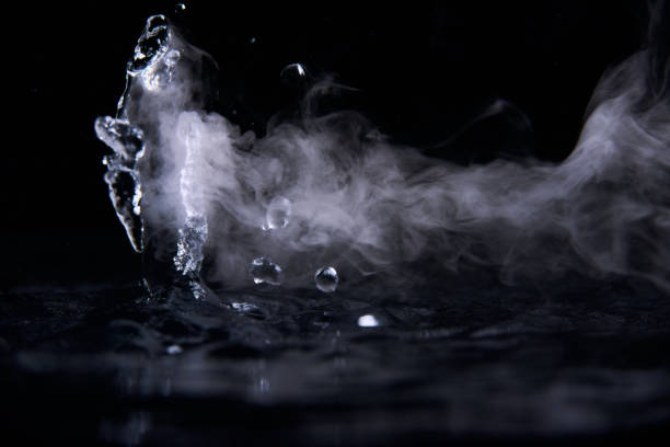 istock Boiling water splash with steam on black background closeup 1203760370