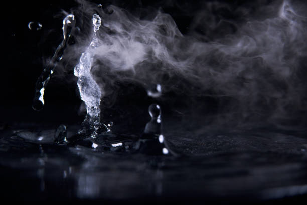 istock Boiling water splash with steam on black background closeup 1203760377