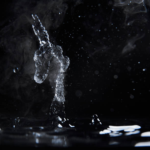 istock Boiling water splash with steam on black background closeup 1203760434