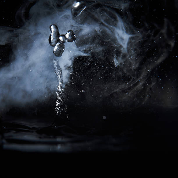 istock Boiling water splash with steam on black background closeup 1203760453