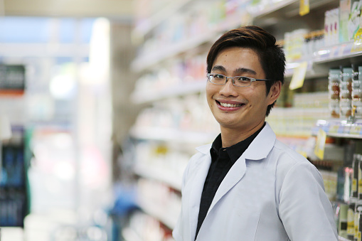 A male adult pharmacist is looking cheerful in pharmacy.