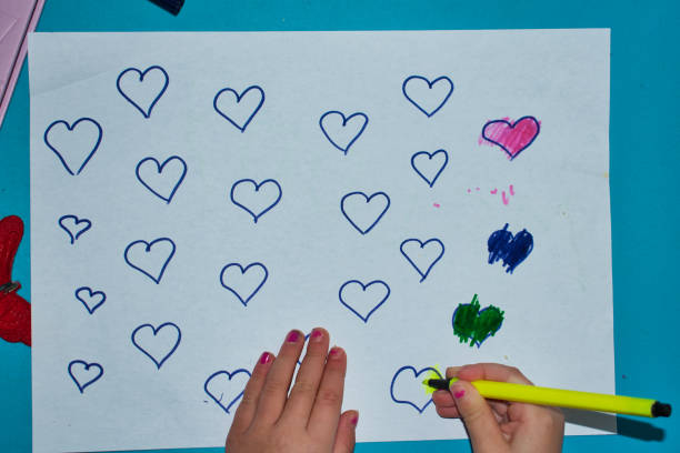 istock A child drawing and colouring love hearts. 1203762179