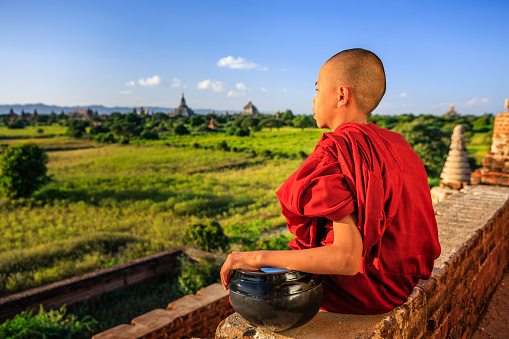 Young Buddhist monk admiring view of ancient temples in Bagan, Myanmar (Burma)