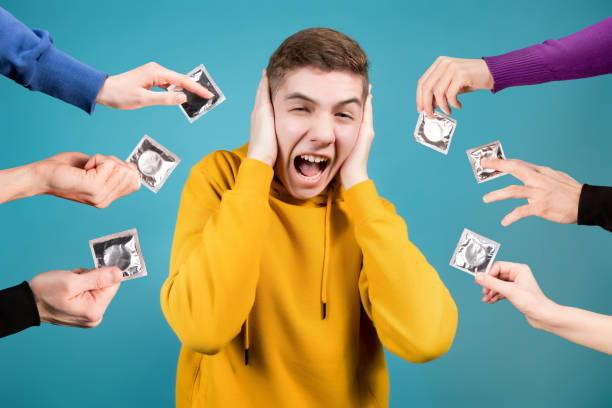 the teenager is shocked by the fact that everyone around him imposes condoms. - sex education condom contraceptive sex imagens e fotografias de stock
