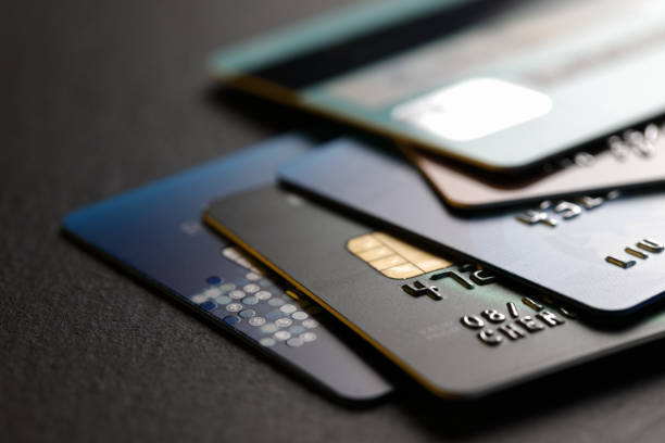 Stacked credit cards stack of multicolored credit cards on black background white collar crime photos stock pictures, royalty-free photos & images