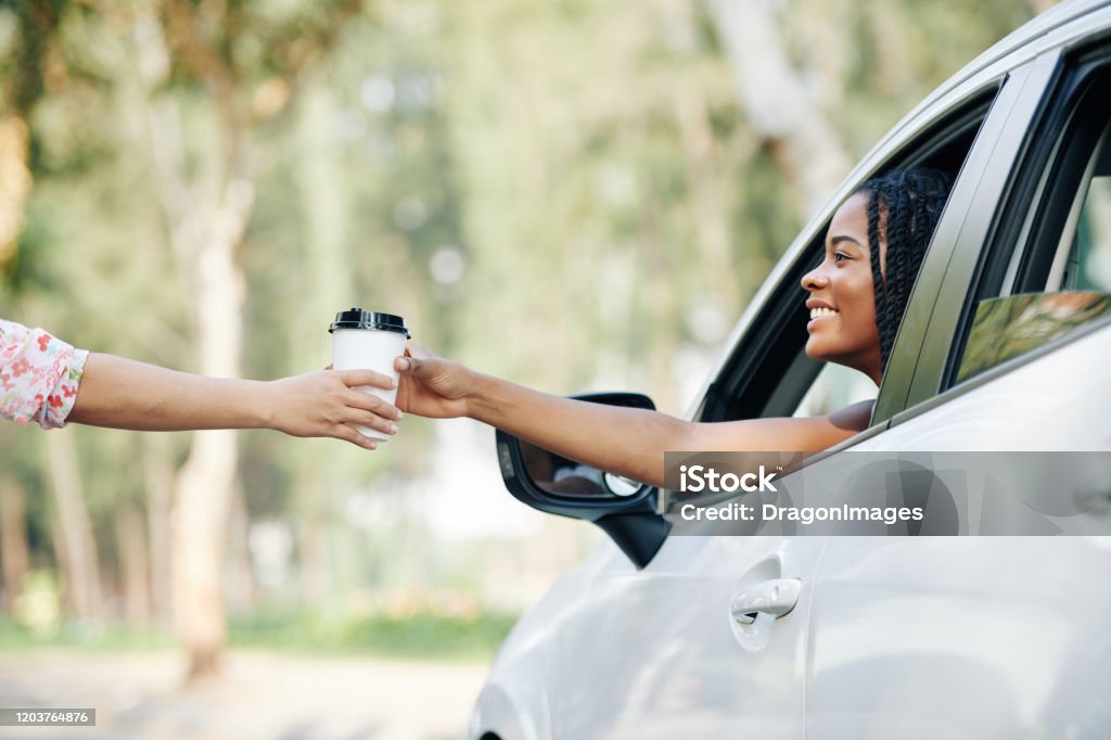 Driver buying morning coffee Happy pretty young Black woman buying coffee in drive through coffeeshop Drive Through Stock Photo