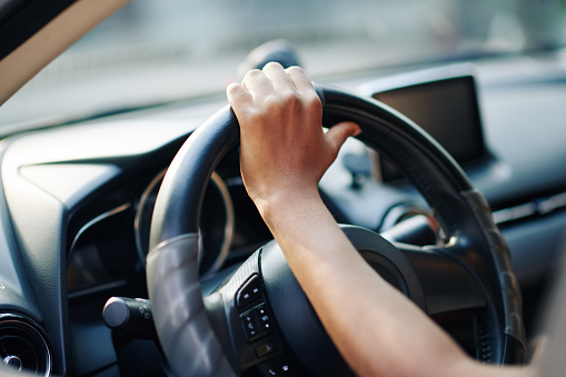 Hand of woman on steering wheel of her new car