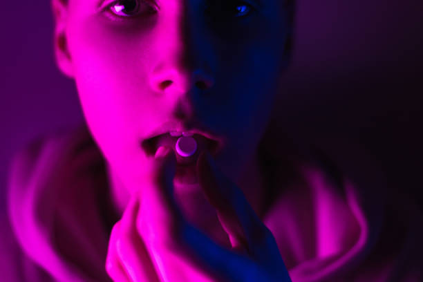 junge teenager in einem rosa hoodie nimmt eine droge in pillen. zunge kerl mit lsd rad. dilated schüler von betäubungsmitteln - narcotic medicine addiction addict stock-fotos und bilder