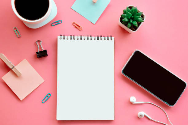business flat lay on pink background with open note pad ,smart phone, paper note and coffee cup