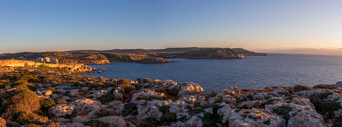 panoramic view on the stunning landscape of the rocky cliffs and golden light on sunset at coastline of the Golden bay, Mediterranean sea island of Malta