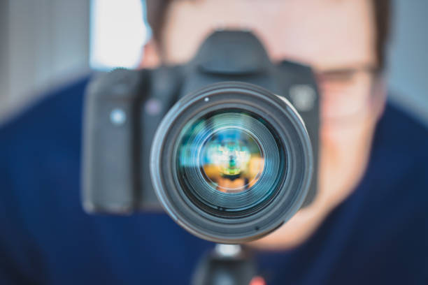 istock Photographer at work: Man is standing behind a professional camera on a tripod, making pictures 1203771590