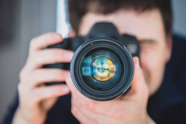 istock Photographer at work: Man is standing behind a professional camera on a tripod, making pictures 1203771634