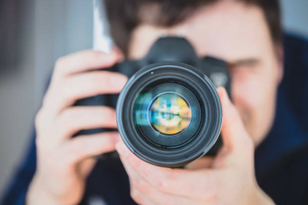 istock Photographer at work: Man is standing behind a professional camera on a tripod, making pictures 1203771647