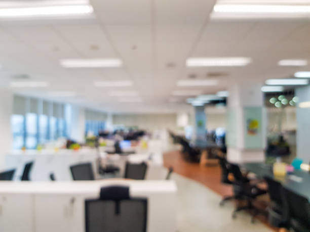 istock Blurred interior of modern office workplace a workspace design without partition decorate with black, white and wooden furniture. Nice environment can create work productivity, relax mood. 1203771969