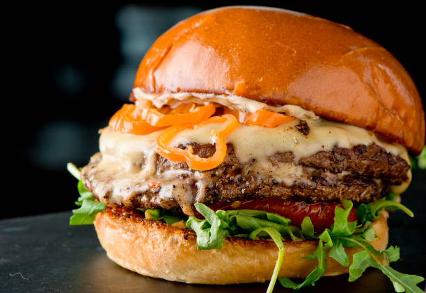 hamburguesa de queso, con queso suizo derretido, tomate de lechuga y cebolla servido en bollo tostado - juicy fotografías e imágenes de stock